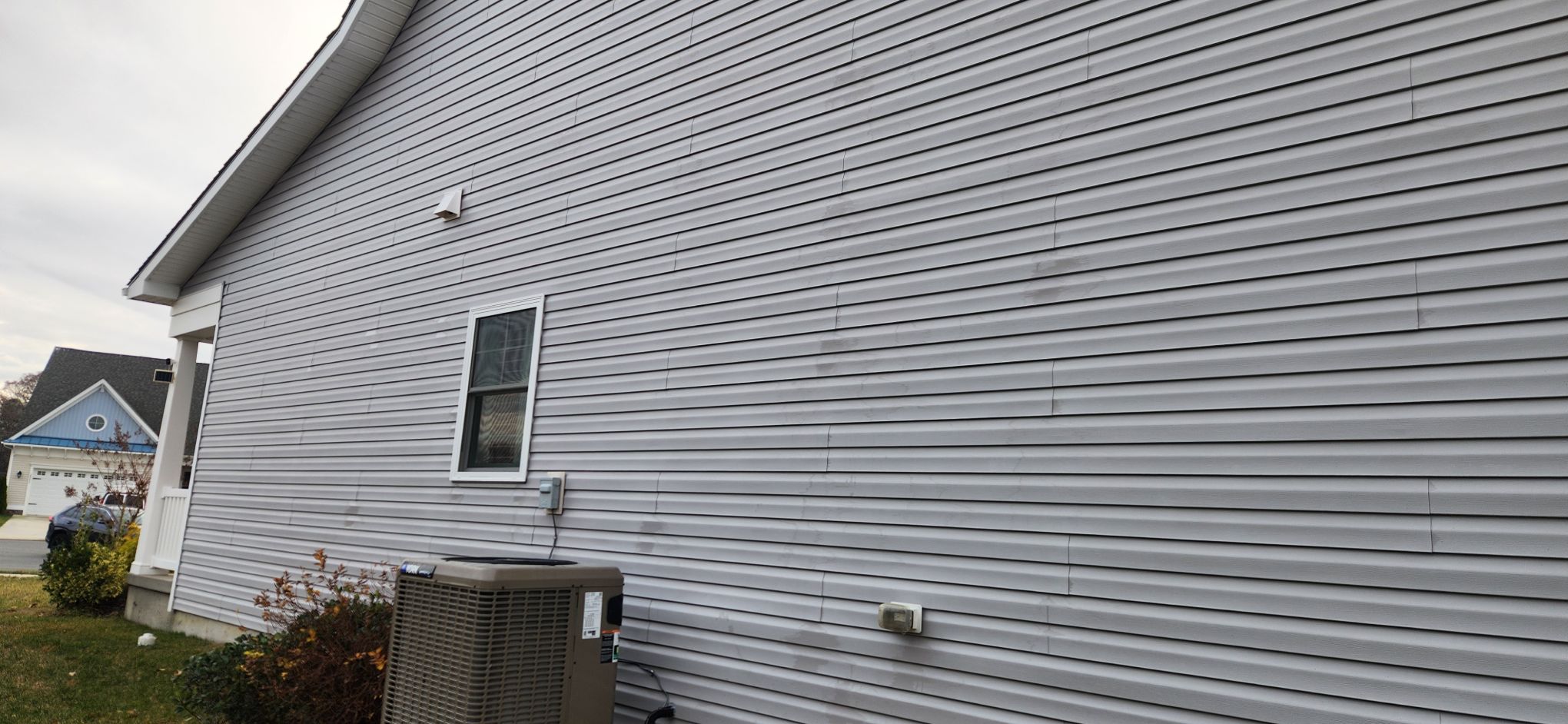 Gray vinyl siding on residential home exterior in Omar, DE with HVAC unit visible
