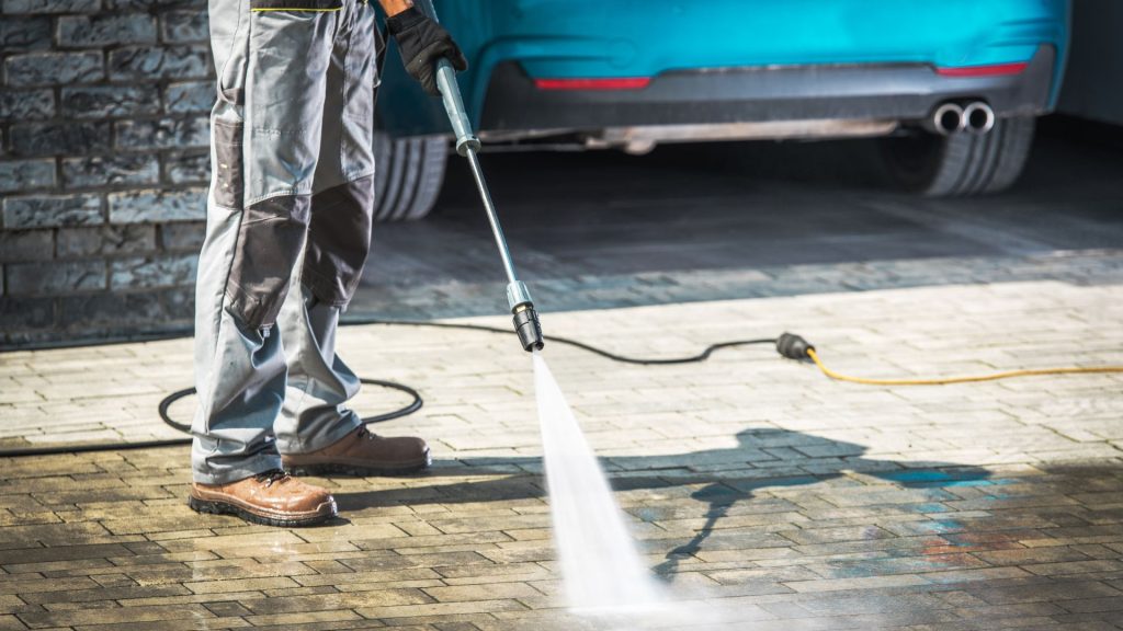 Professional cleaning driveway with high-pressure washer spray in Millsboro DE residential area