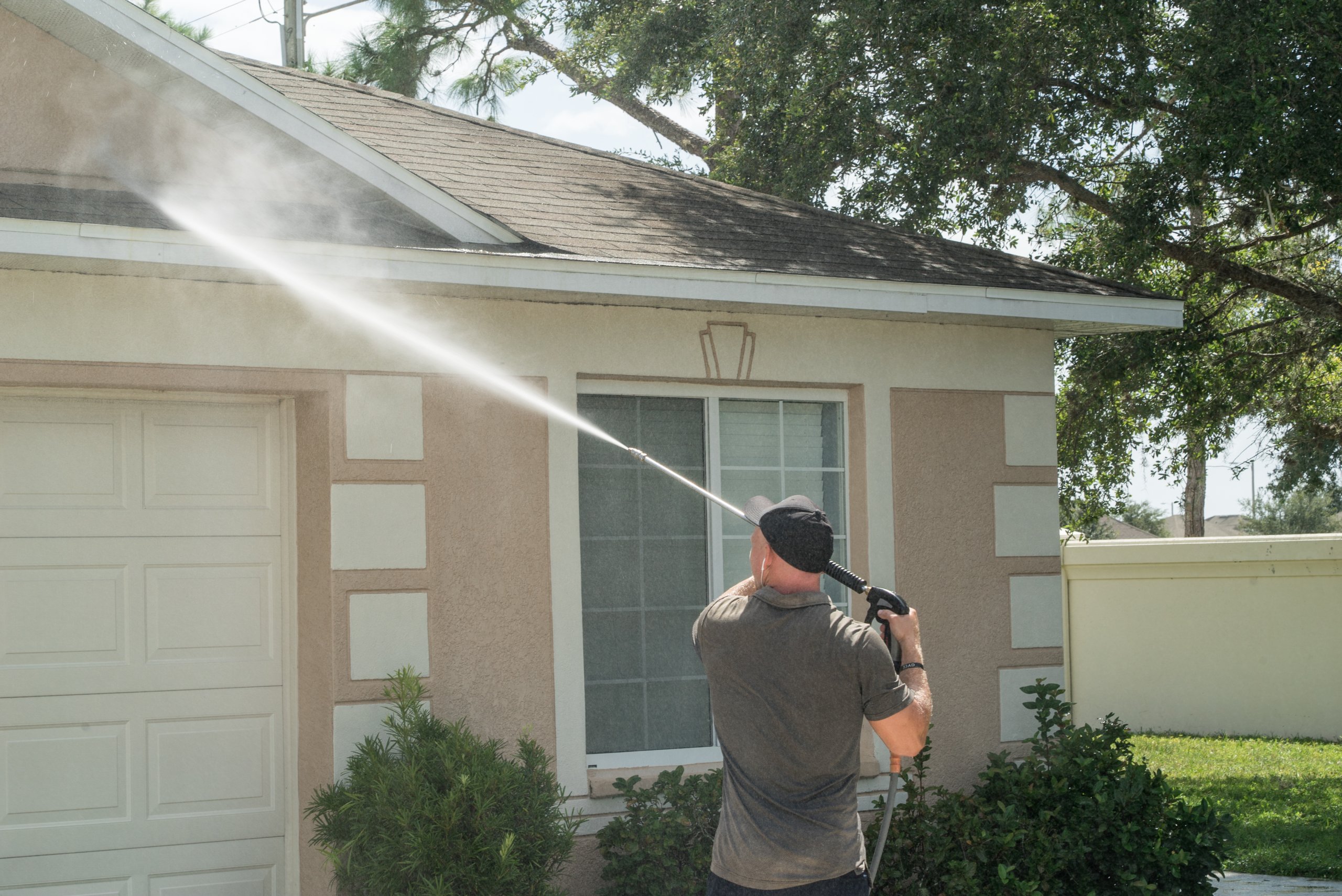 Professional cleaning worker pressure washing brick home exterior in Prime Hook, DE area